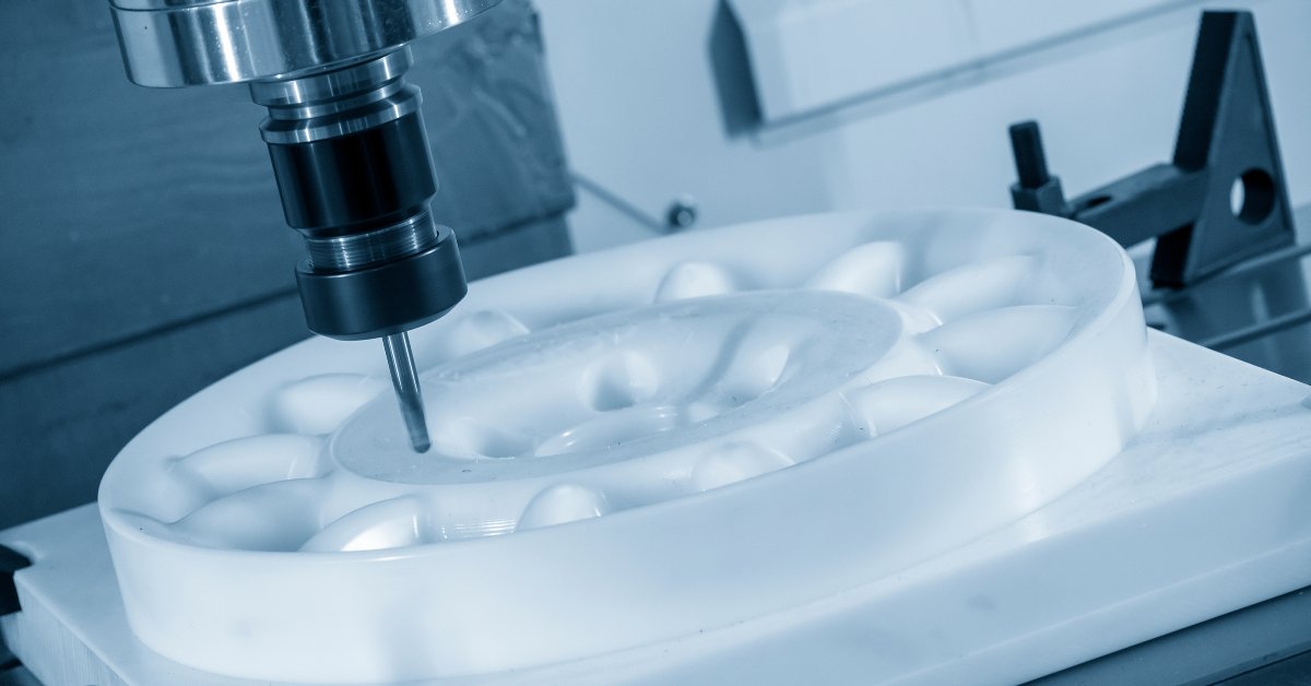 A close-up of the CNC milling machine cutting an engineering plastic part using a solid ball end-mill tool.